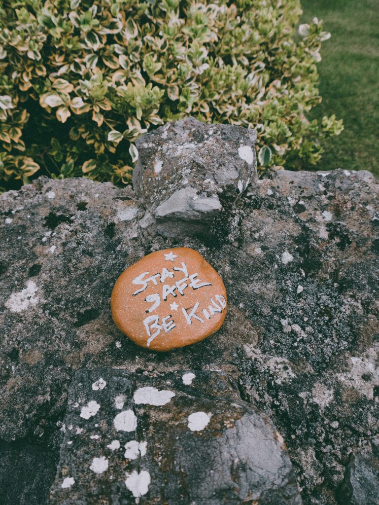 rock with the words "stay safe, be kind" on it